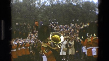 1969: a colorful parade of military musical band in a park before a crowd