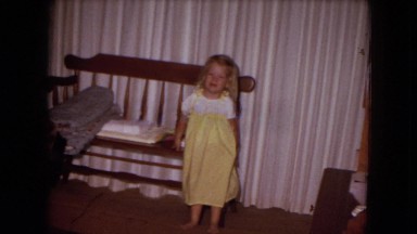 1970: Baby Girl Poses for Camera in Yellow Dress at White Sands, Florida