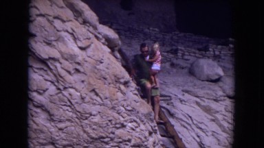 1973: young man and his baby at a place with ruins, climbing down a ladder