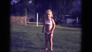1973: young girl in bathing suit running toward her family while smiling