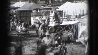 1948: a troupe of men and women riding around the corner of an encampment.
