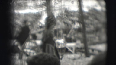 1948: woman carries two birds in cages, people follow carrying large crate