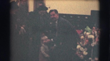 1959: a man squatting in front of a little boy and adjusting his suit and coat