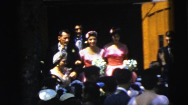 1961: group of well-dressed individuals emerge smiling from behind wooden door