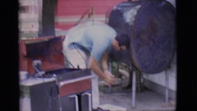 1968: a man closing the lid of a grill and entering a home through a doorway