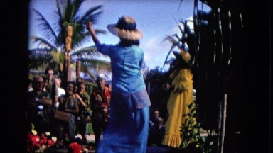 1968: a hawaiian scene where a lady dressed in blue is dancing for an audience