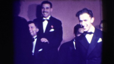 1941: men gathering in tuxedos raising their arms and clapping their hands NY
