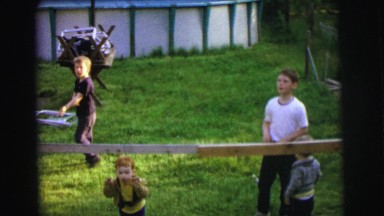 1972: young children amusing themselves in a backyard on a bright sunny day
