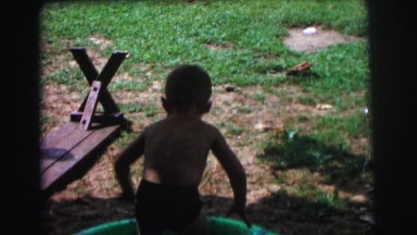 1972: two small children in playing in the water in a small swimming pool