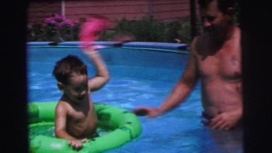 1972: father playing with his son in the pool with floating tube LYNBROOK