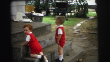 1972: children in matching clothes on staircase watch newspaper flutter
