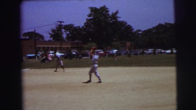1972: boys in uniform playing a game of baseball on the field LYNBROOK, NEW YORK