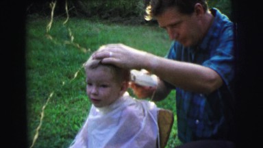 1972: the boy enjoys cute hair cut by his father at the garden LYNBROOK