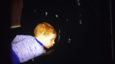 1972: a cute redheaded boy climbing in and out of a leather arm chair LYNBROOK