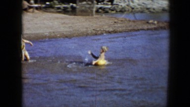 1959: two children splash each other while adults swim in a lake. DISNEYLAND,