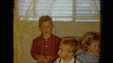 1959: six children sitting around a kitchen table who look like they are ready