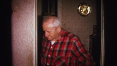 1972: older man in red plaid shirt entering room motions for folks