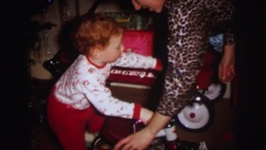 1972: a cute young red headed boy climbing on a tricycle LYNBROOK, NEW YORK