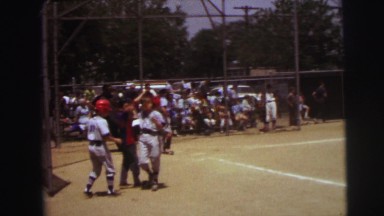1972: an older boy in a gray baseball uniform and red batters cap is up to bat