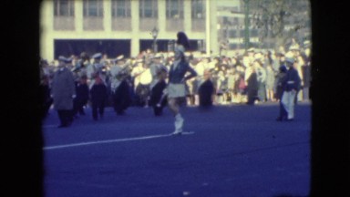 1948: marching band led down the street of a parade downtown city woman leads