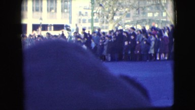 1948: marching band leads parade down street while crowd watches and cheers