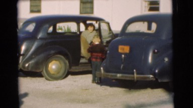 1951: chid consulting with their mom in the parking lot of the family car