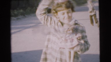 1951: young children run after camera down street and brother takes hat off