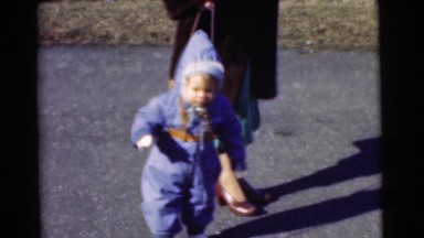 1951: baby boy walking with a woman on a winter day outside with a leash