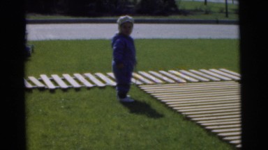 1951: two toddlers playing on a grass courtyard with wooden walkways CHATHAM,