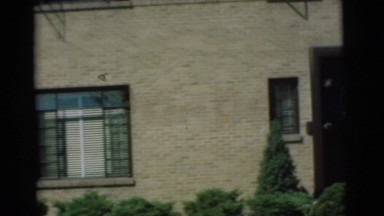 1951: a lovely home with an attached garage, showing part of a car inside of it.