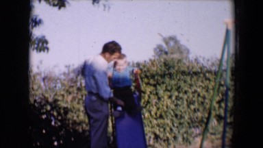 1958: a man helps a young boy slide down a slide. TUCSON, ARIZONA