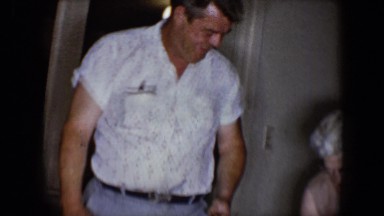 1958: man holds and then tickles young boys on floor who appear to be twins