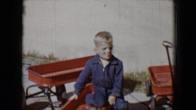 1958: little blond boy sitting on red wagon with other wagons TUCSON, ARIZONA