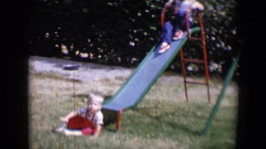 1958: two kids playing on a slide in a park with dried grassy ground TUCSON,