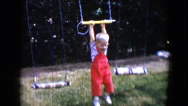 1958: toddler and brother play on jungle gym set very animated having fun