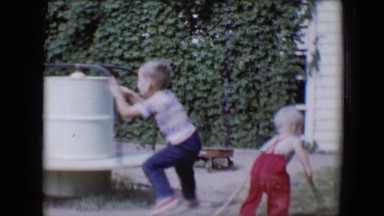 1958: two funny boys playing on a revolving ride near to a greenery TUCSON,