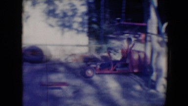 1958: boy riding his small red ride-on car around a dirt yard TUCSON, ARIZONA