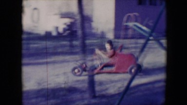 1958: kid in car shows off while driving on playground while waving TUCSON,