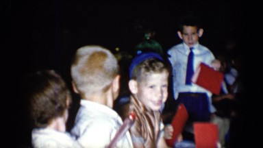1958: a group of well dressed small children in a row of seats with red folders