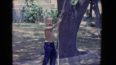 1958: a little boy playing with a rope tied to a tree in a yard TUCSON, ARIZONA