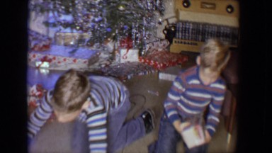 1958: twin brothers wearing striped shirts and blue jeans opening gifts