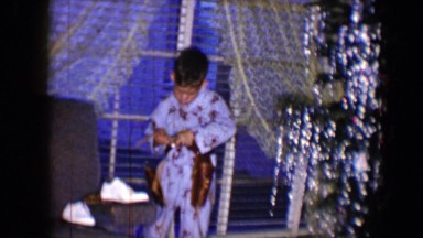 1959: a boy standing and fastening his belt over the dress DISNEYLAND,