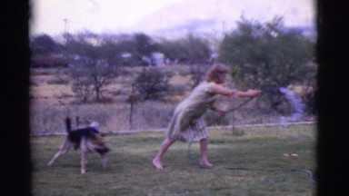 1968: outdoor woman plays with german shepherd and kids using garden hose