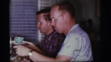 1968: a man with smiling face is eating with friends. COTTONWOOD, ARIZONA