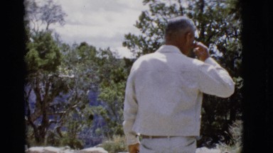 1968: man walks towards trees and view of mountains slowly before admiring view