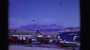 1968: various boats on a beautiful lake with mountains in the background