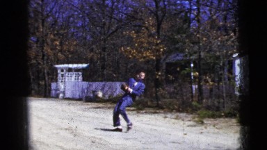 1956: man wearing suit and baseball mitt playing catch on an old road NEW YORK