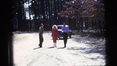 1956: three well dressed people walking down the street smoking cigarettes