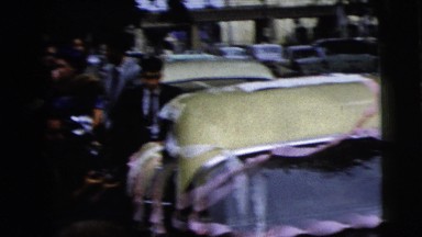 1962: gathering of people around a car after a wedding talking and waiting