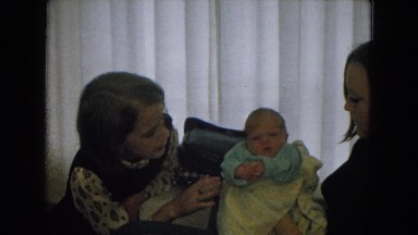 1967: a woman with brown hair holding a young baby, and a young girl sitting